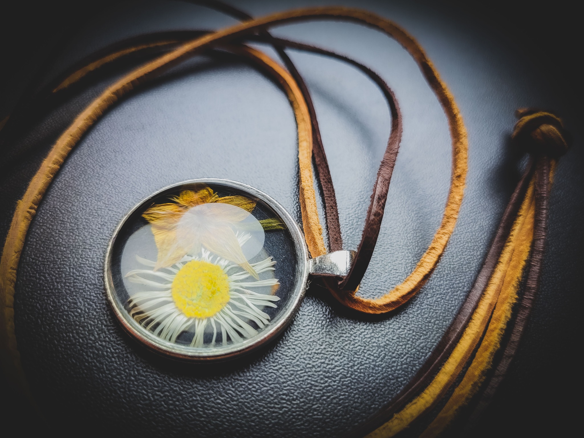 szklany wisior z ususzonymi kwiatami, na skórzanym rzemyku