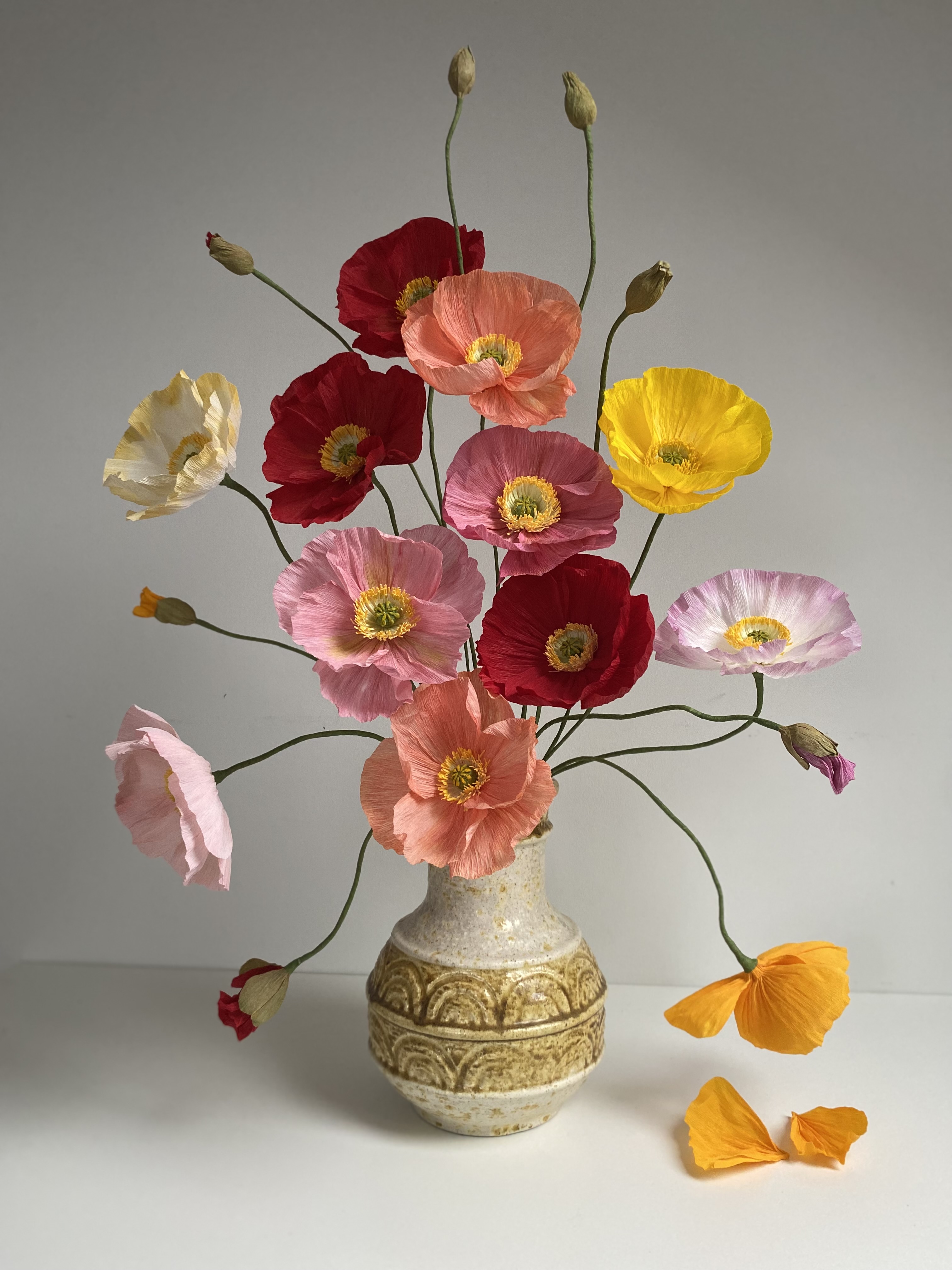 kolorowe maki z bibuły w jasnym wazonie, na białym tle