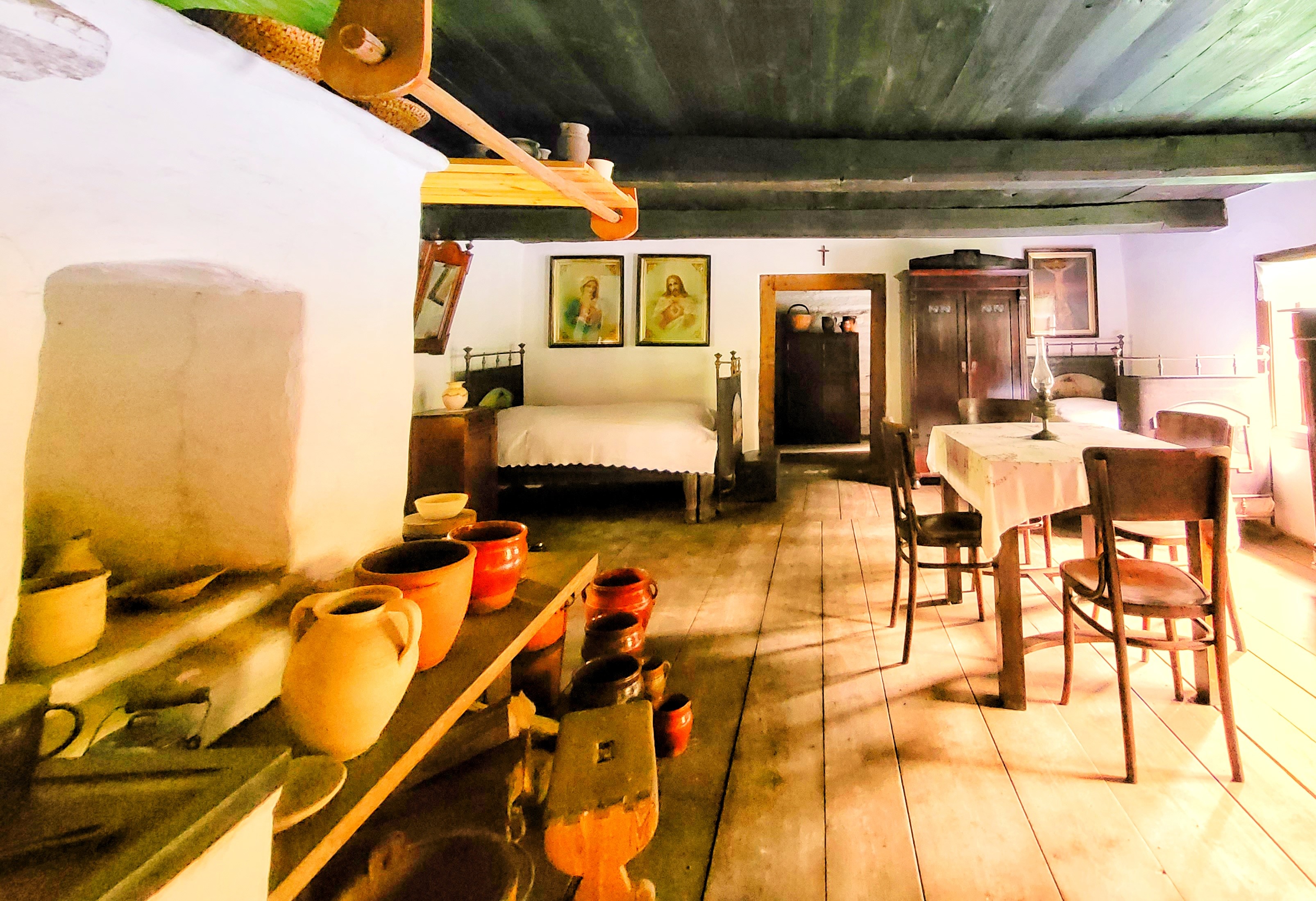 wnętrze starej izby w chałupie z glinianym piecem, drewnianymi meblami, glinianymi garnkami na piecu